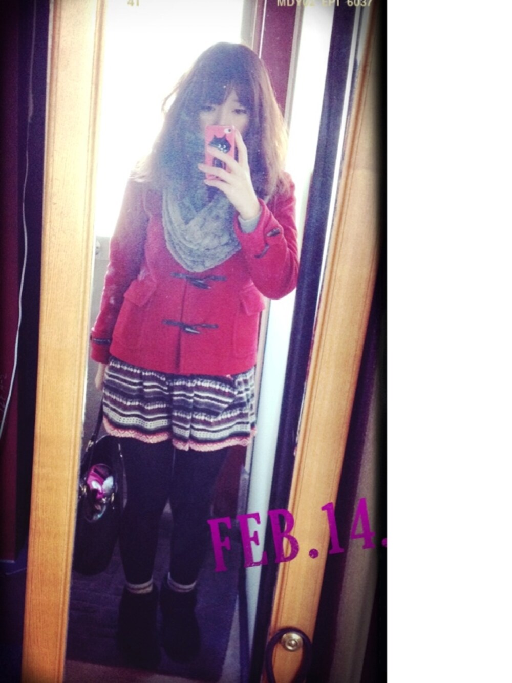 レッド系のダッフルコート、ブラック系のブーツを着用したレディースの冬コーディネートの1枚目の写真
