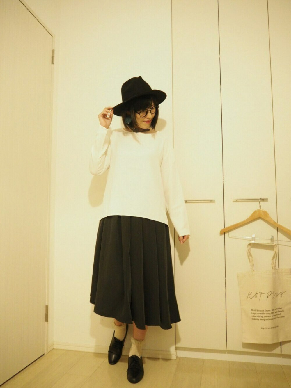 ホワイト系のトップス、ブラック系のスカート、ブラック系のハットを着用したレディースの夏コーディネートの1枚目の写真