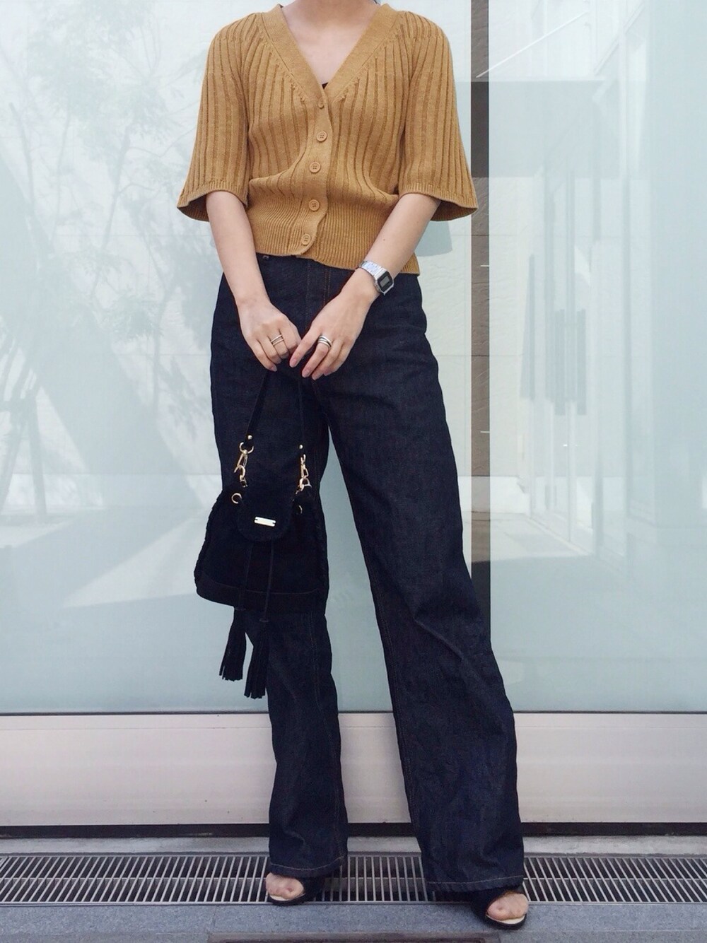 イエロー系のニット/セーター、ブルー系のデニムパンツ、ブラック系のサンダルを着用したレディースの春コーディネートの1枚目の写真