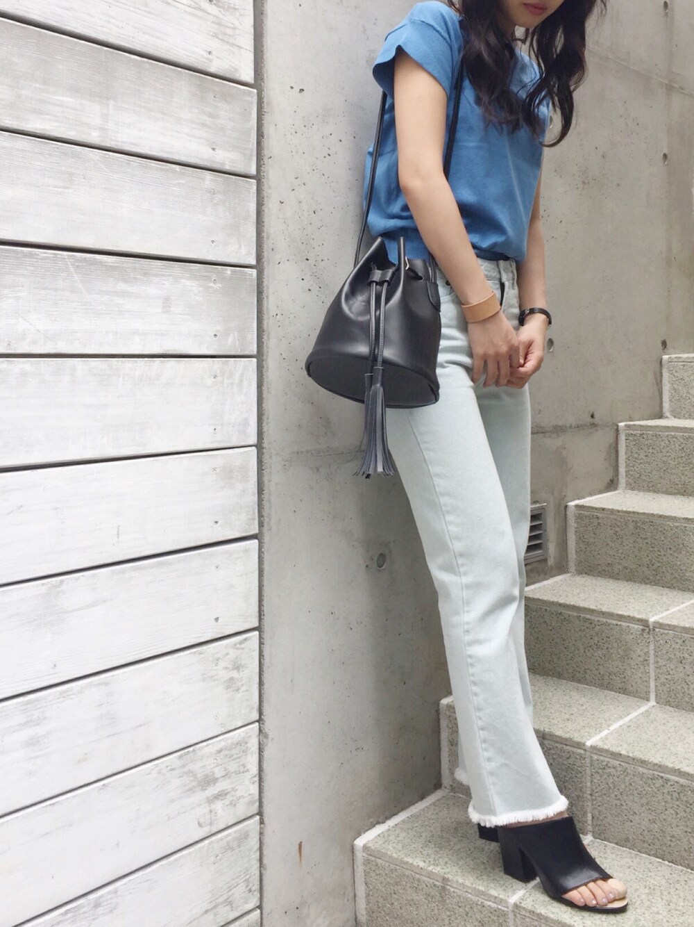 ブルー系のニット/セーター、ブラック系のバッグ、ブルー系のデニムパンツを着用したレディースの春コーディネートの1枚目の写真