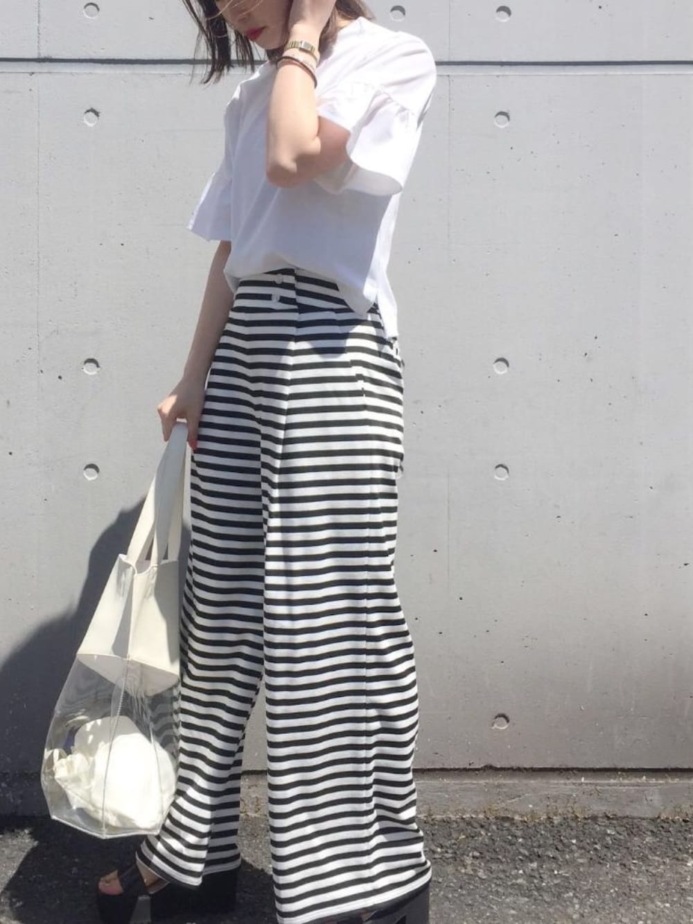 ホワイト系のトップス、ブラック系のパンツ、ホワイト系のバッグを着用したレディースの春コーディネートの1枚目の写真