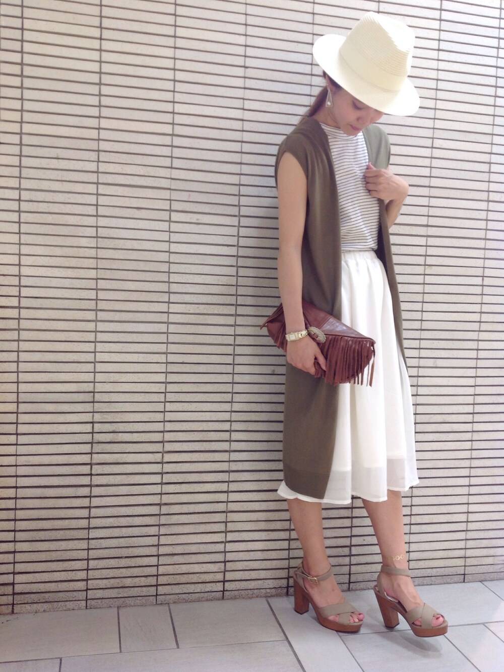 ブラウン系のクラッチバッグ、ホワイト系のタンクトップ、ホワイト系のスカートを着用したレディースの夏コーディネートの1枚目の写真