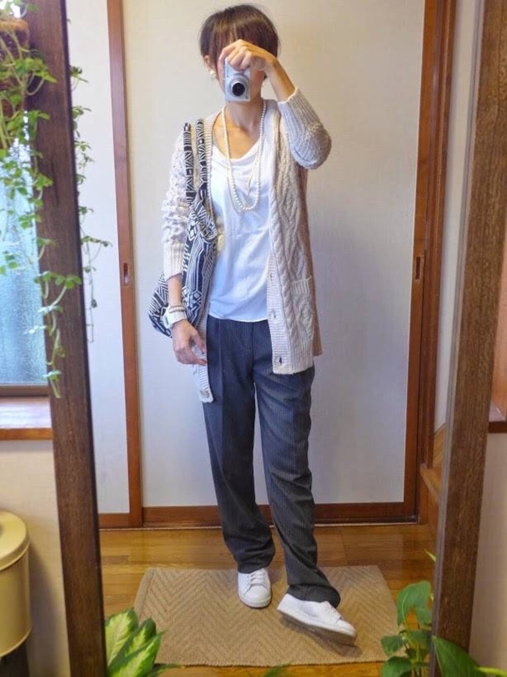 ショルダーバッグ、ホワイト系のスニーカー、ホワイト系のイヤリングを着用したレディースの秋コーディネートの1枚目の写真