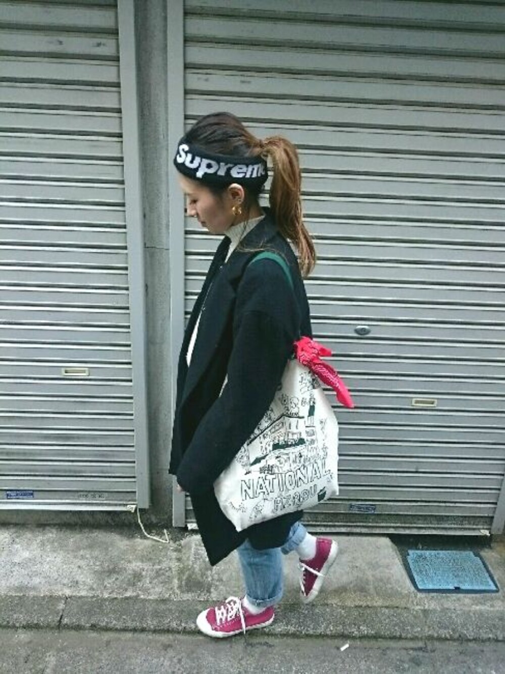 ブラック系のチェスターコート、ブルー系のデニムパンツ、ブラック系のヘアバンドを着用したレディースの冬コーディネートの1枚目の写真