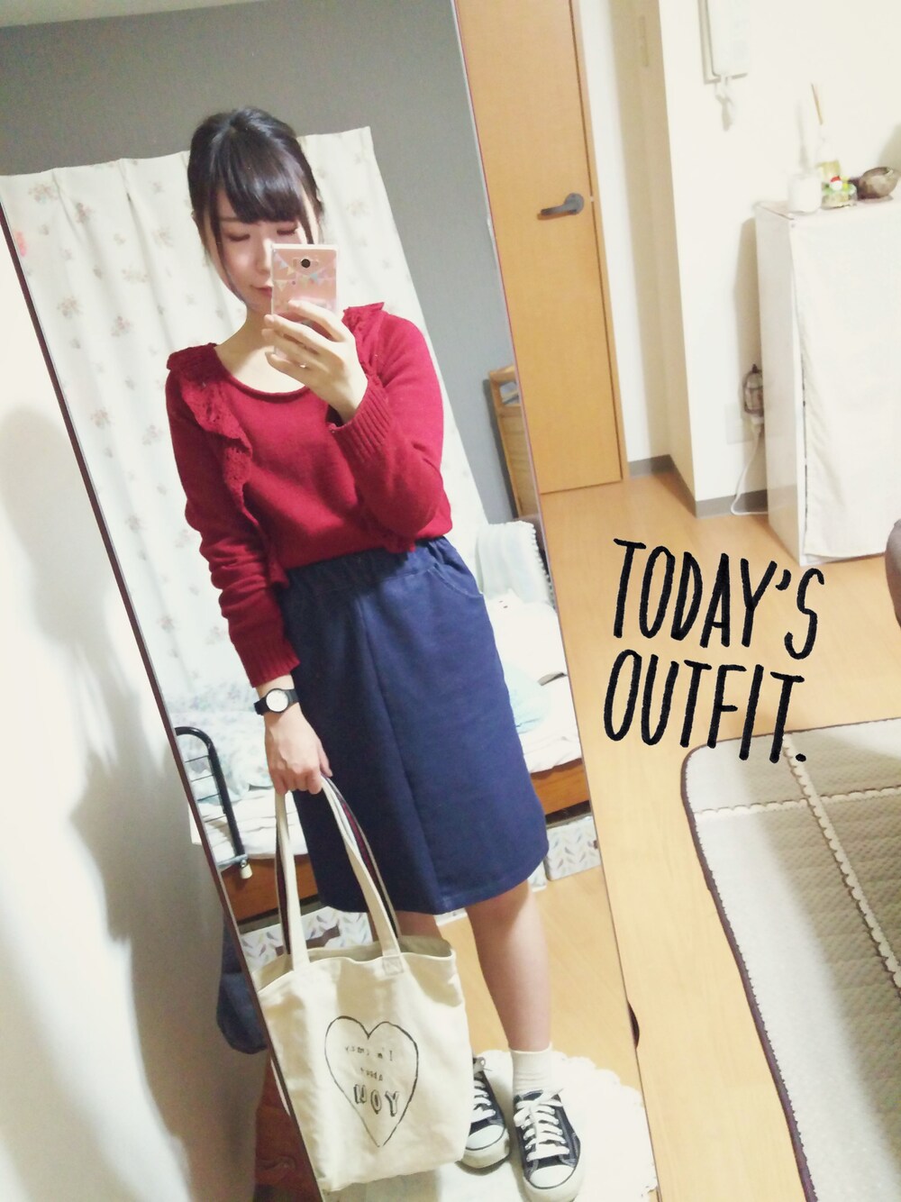 レッド系のニット/セーター、ブルー系のスカート、ブラック系のスニーカーを着用したレディースの秋コーディネートの1枚目の写真