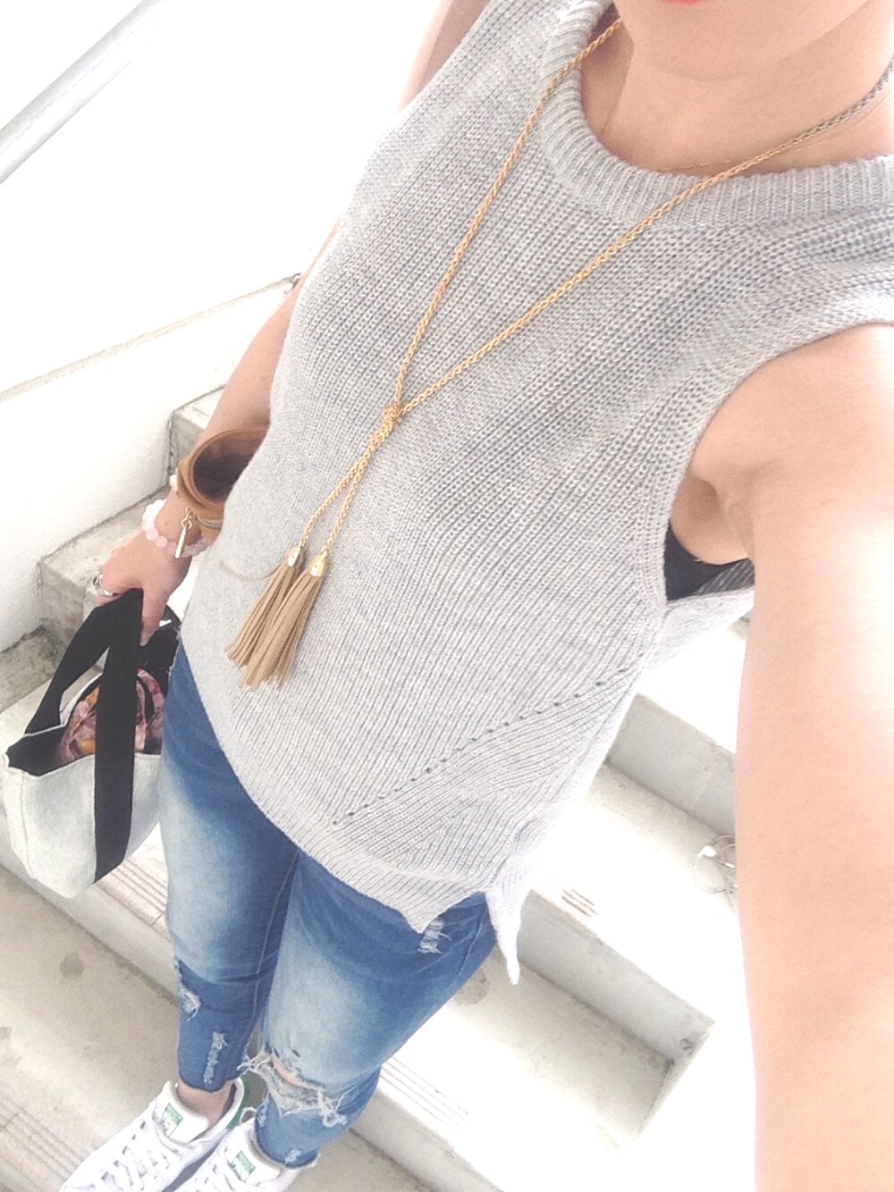 グレー系のベスト、ホワイト系のスニーカー、ブルー系のデニムパンツを着用したレディースの春コーディネートの1枚目の写真