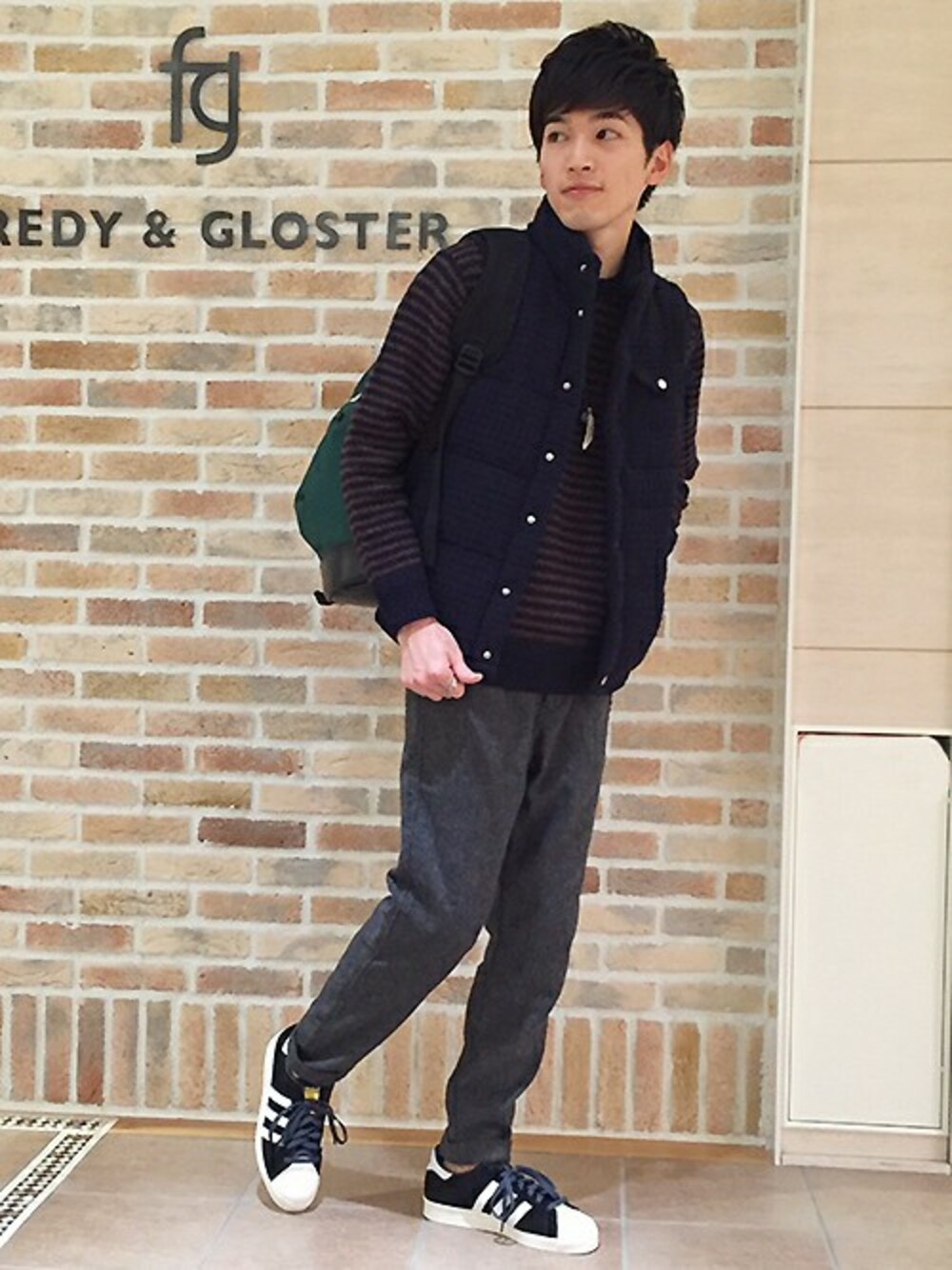 ブラウン系のニット/セーター、グレー系のその他パンツ、グリーン系のバックパック/リュックを着用したメンズの秋コーディネートの1枚目の写真