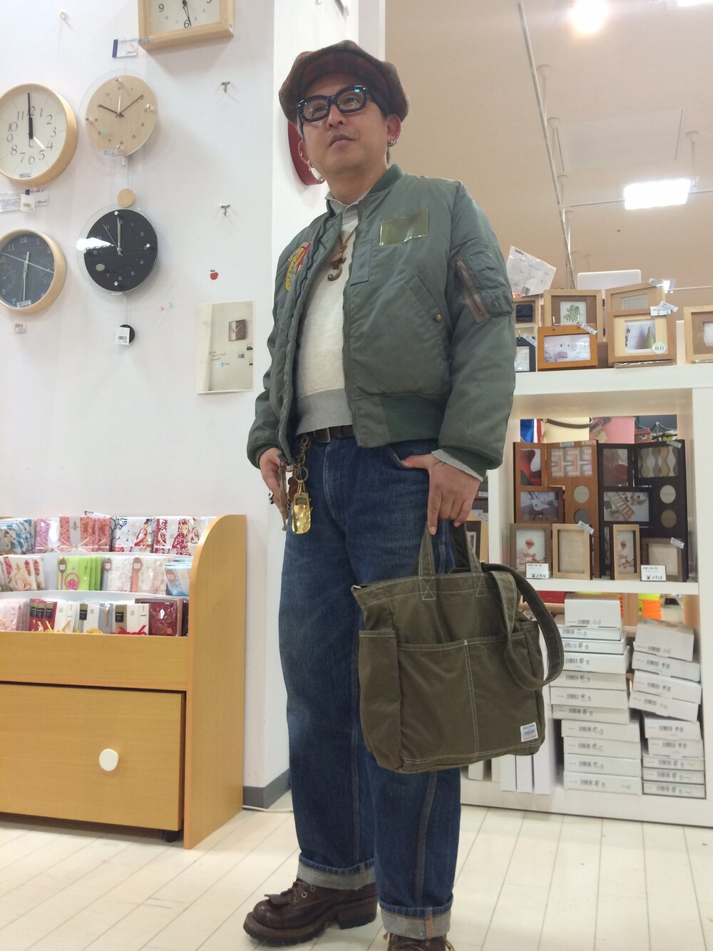 グレー系のナイロンジャケット、ブルー系のデニムパンツ、グリーン系のトートバッグを着用したメンズの冬コーディネートの1枚目の写真