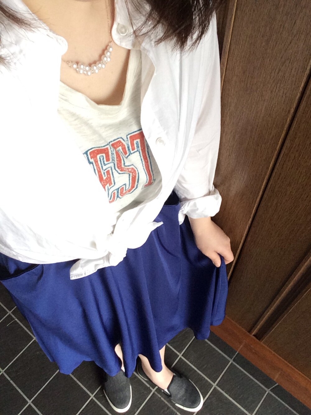 ブルー系のスカート、ブラック系のスニーカー、ホワイト系のTシャツ/カットソーを着用したレディースの春コーディネートの1枚目の写真