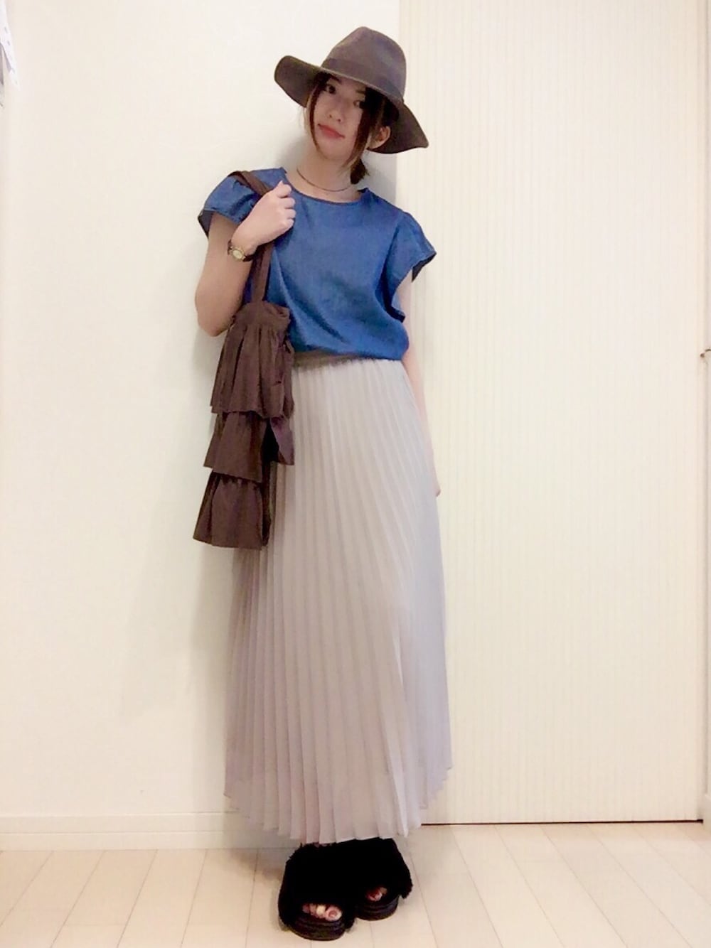 グレー系のスカート、ブルー系のトップス、ブラウン系のトートバッグを着用したレディースの夏コーディネートの1枚目の写真