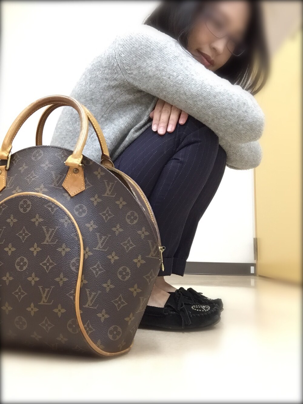 グレー系のニット/セーター、ブラック系のスラックス、ブラウン系のハンドバッグを着用したレディースの冬コーディネートの1枚目の写真