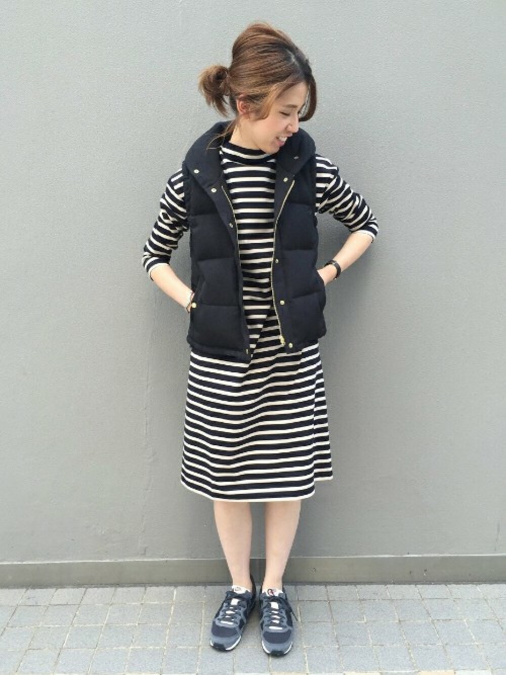 ブルー系のワンピース、ブラック系のダウンベスト、ブラック系のスニーカーを着用したレディースの夏コーディネートの1枚目の写真