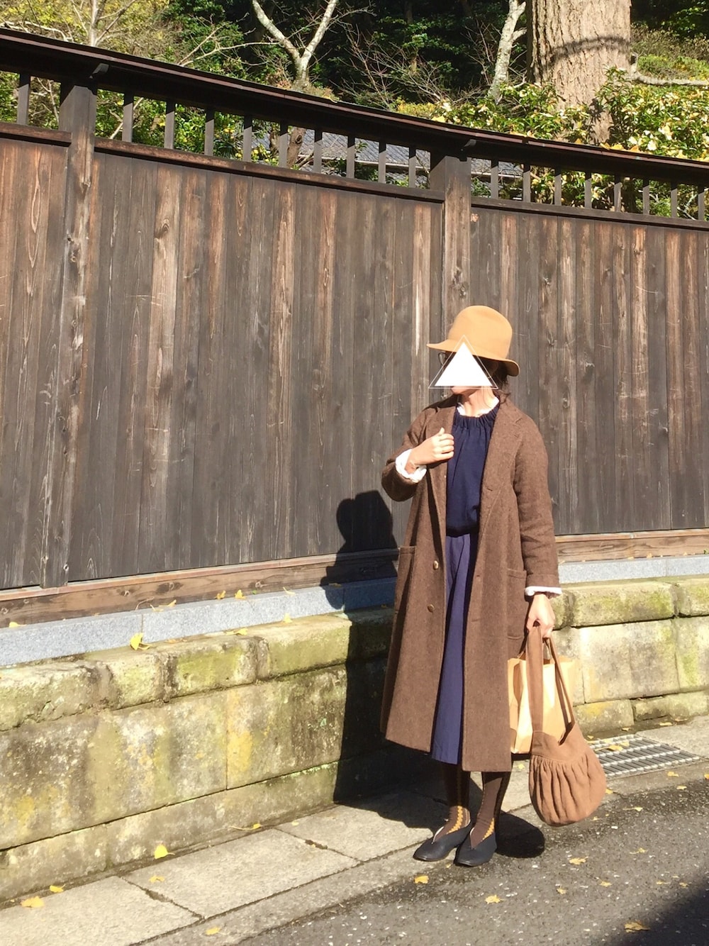 ブルー系のトップス、ブルー系のスカート、ブラウン系のハンドバッグを着用したレディースの秋コーディネートの1枚目の写真