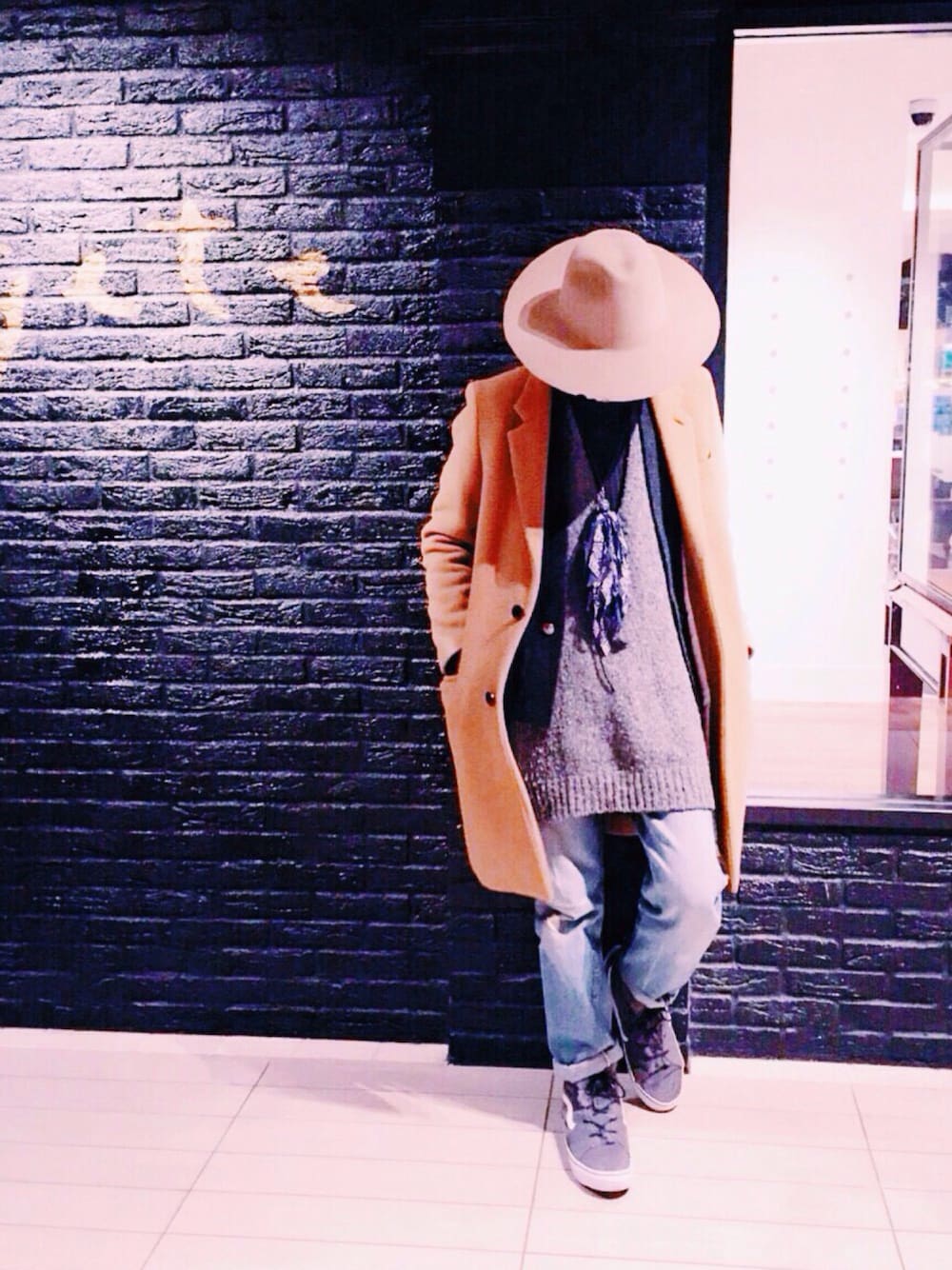 ベージュ系のチェスターコート、ブルー系のデニムパンツ、グレー系のワンピースを着用したメンズの冬コーディネートの1枚目の写真