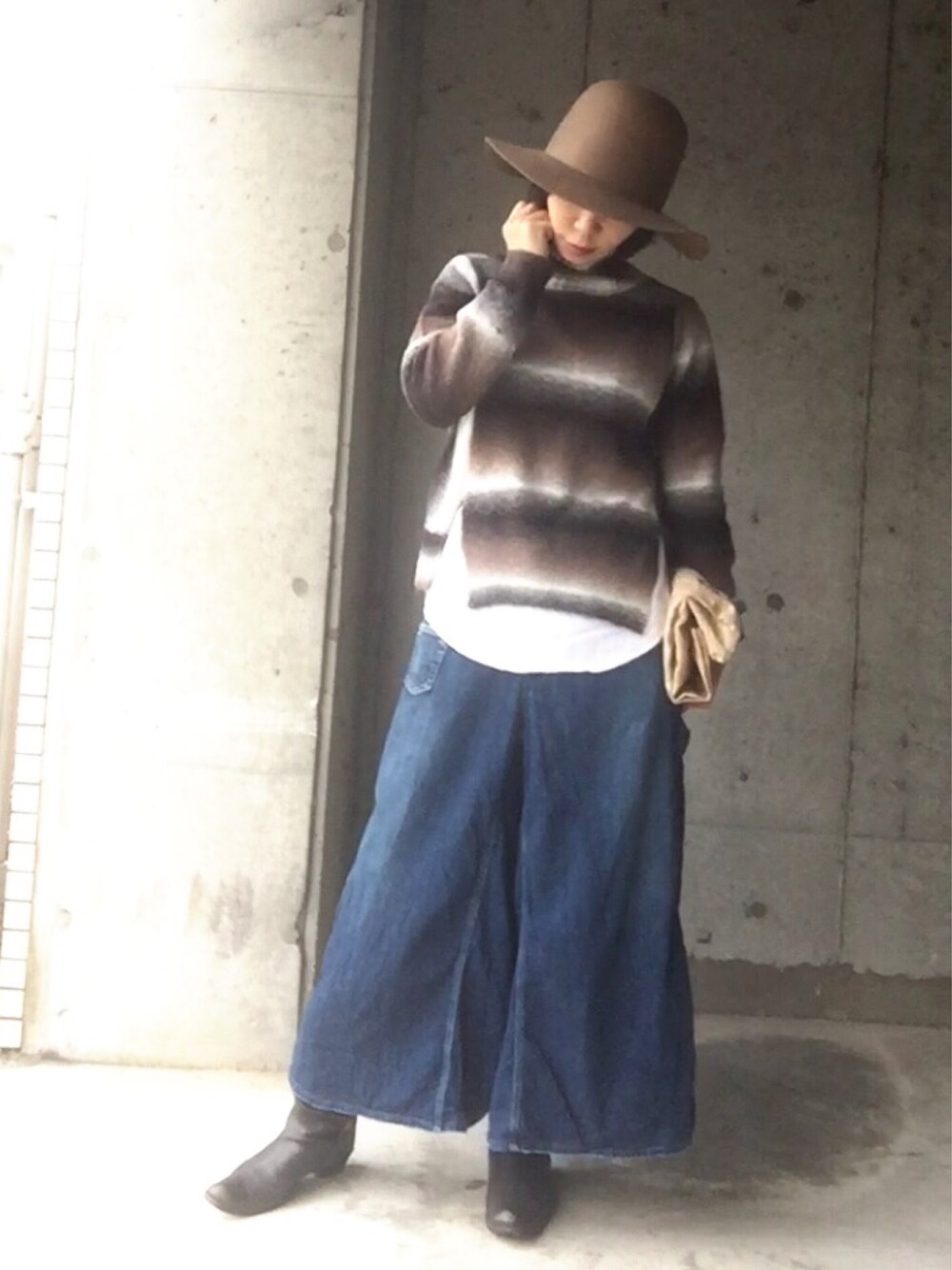 ブラウン系のニット/セーター、ブルー系のデニムパンツ、ベージュ系のクラッチバッグを着用したレディースの冬コーディネートの1枚目の写真