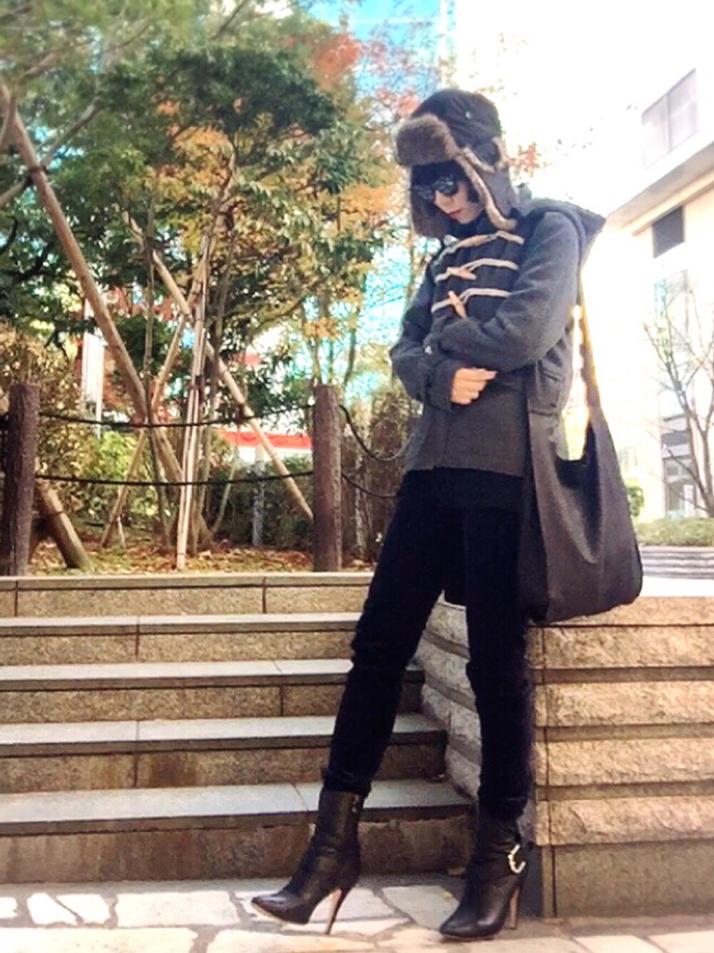 グレー系のダッフルコート、ブラック系のトップス、ブラック系のショルダーバッグを着用したレディースの冬コーディネートの1枚目の写真