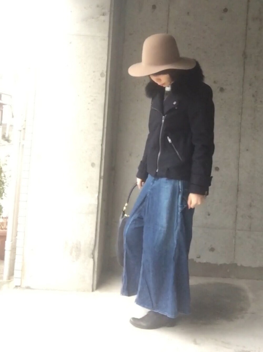 ブルー系のライダースジャケット、ブルー系のデニムパンツ、ブラウン系のニット/セーターを着用したレディースの冬コーディネートの1枚目の写真