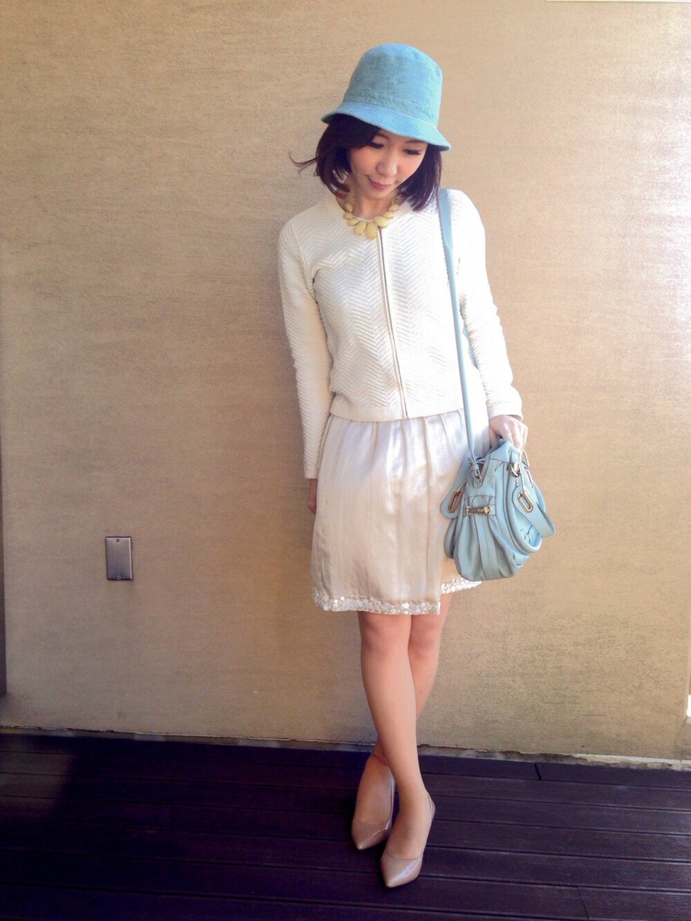 ホワイト系のカーディガン/ボレロ、ベージュ系のパンプス、ホワイト系のスカートを着用したレディースの春コーディネートの1枚目の写真