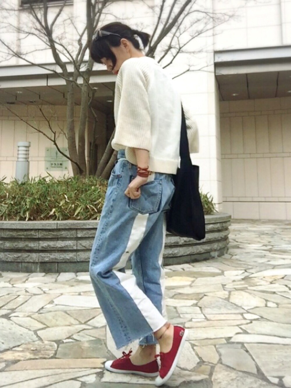 ブルー系のデニムパンツ、ブラック系のショルダーバッグ、ベージュ系のニット/セーターを着用したレディースの春コーディネートの1枚目の写真