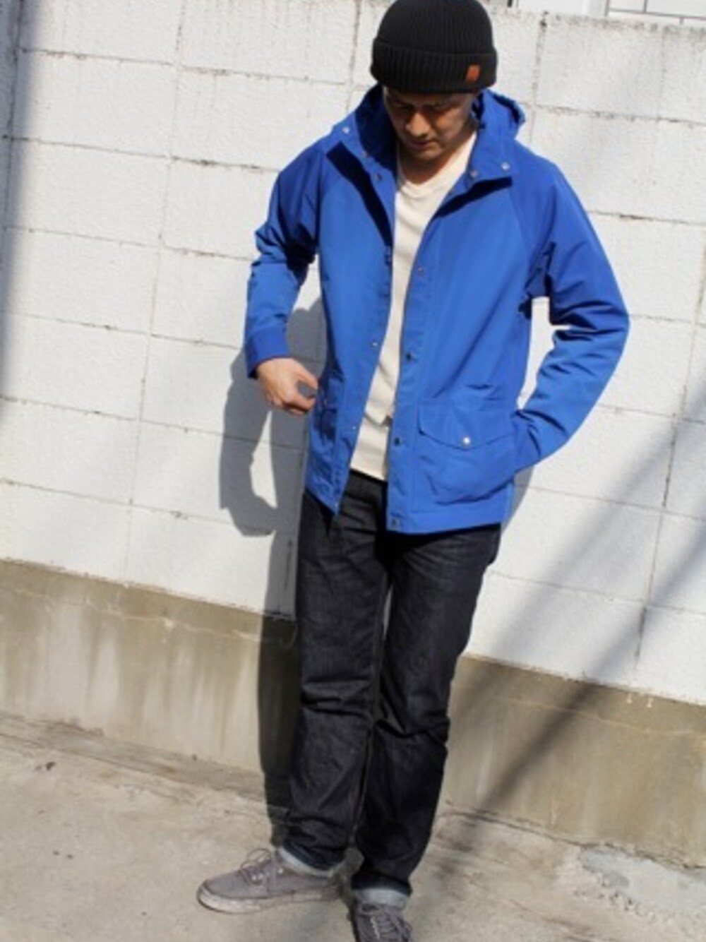 ブルー系のマウンテンパーカー、ブルー系のデニムパンツ、ブラック系のスニーカーを着用したメンズの春コーディネートの1枚目の写真