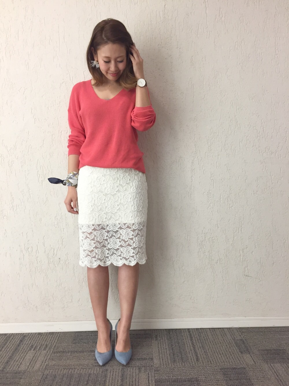 ピンク系のニット/セーター、ホワイト系のスカート、ブルー系のパンプスを着用したレディースの春コーディネートの1枚目の写真
