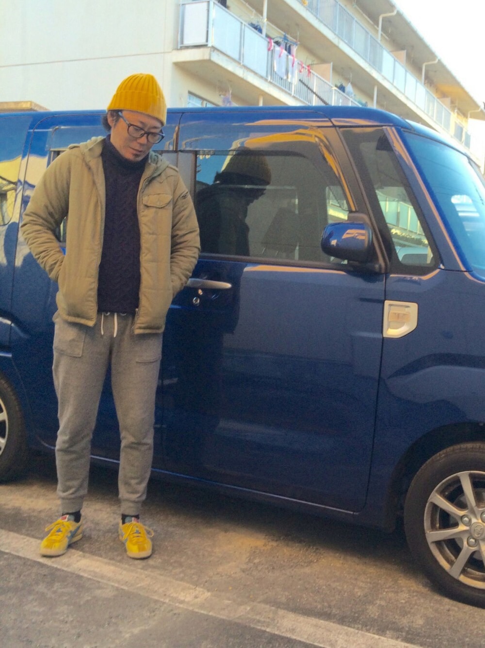 ブラック系のパンツ、イエロー系のスニーカー、ブルー系のニット/セーターを着用したメンズの冬コーディネートの1枚目の写真