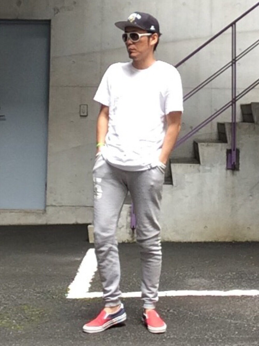 グレー系のパンツ、レッド系のスニーカー、ホワイト系のTシャツ/カットソーを着用したメンズの夏コーディネートの1枚目の写真