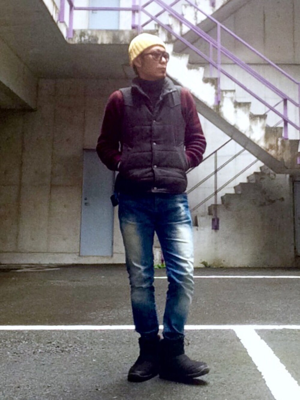 ブラック系のブーツ、ブラウン系のニット/セーター、グレー系のダウンベストを着用したメンズの秋コーディネートの1枚目の写真