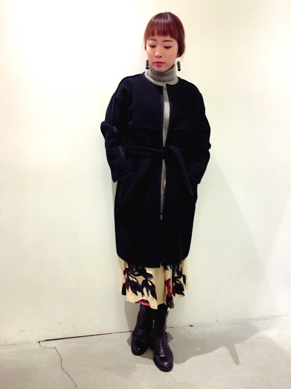 ブラック系のノーカラージャケット、ブラック系のブーツ、ブルー系のピアス(両耳用)を着用したレディースの冬コーディネートの1枚目の写真