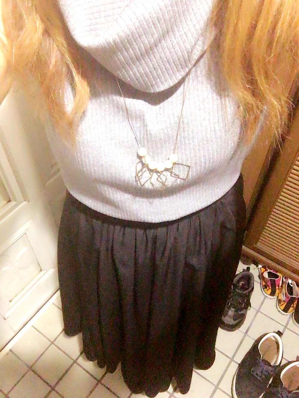 グレー系のTシャツ/カットソー、ブラック系のスカート、ブラック系のブーツを着用したレディースの秋コーディネートの1枚目の写真
