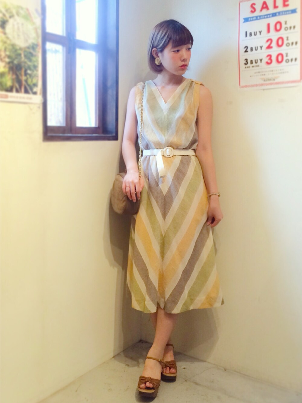 イエロー系のワンピース、ブラウン系のサンダルを着用したレディースの夏コーディネートの1枚目の写真