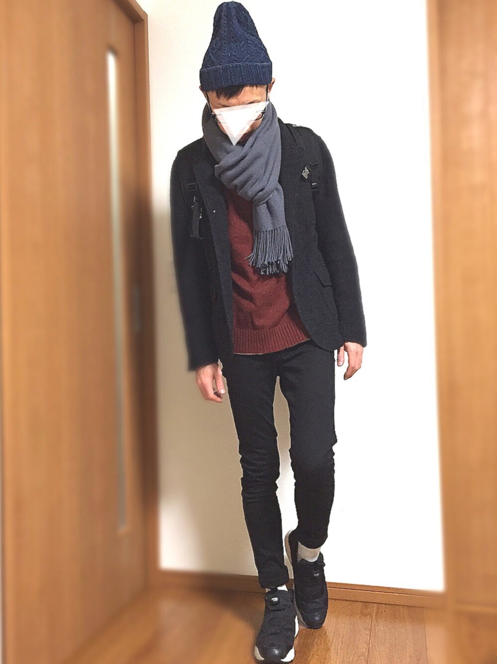 レッド系のニット/セーター、ブラック系のテーラードジャケット、ブラック系のスニーカーを着用したメンズの冬コーディネートの1枚目の写真