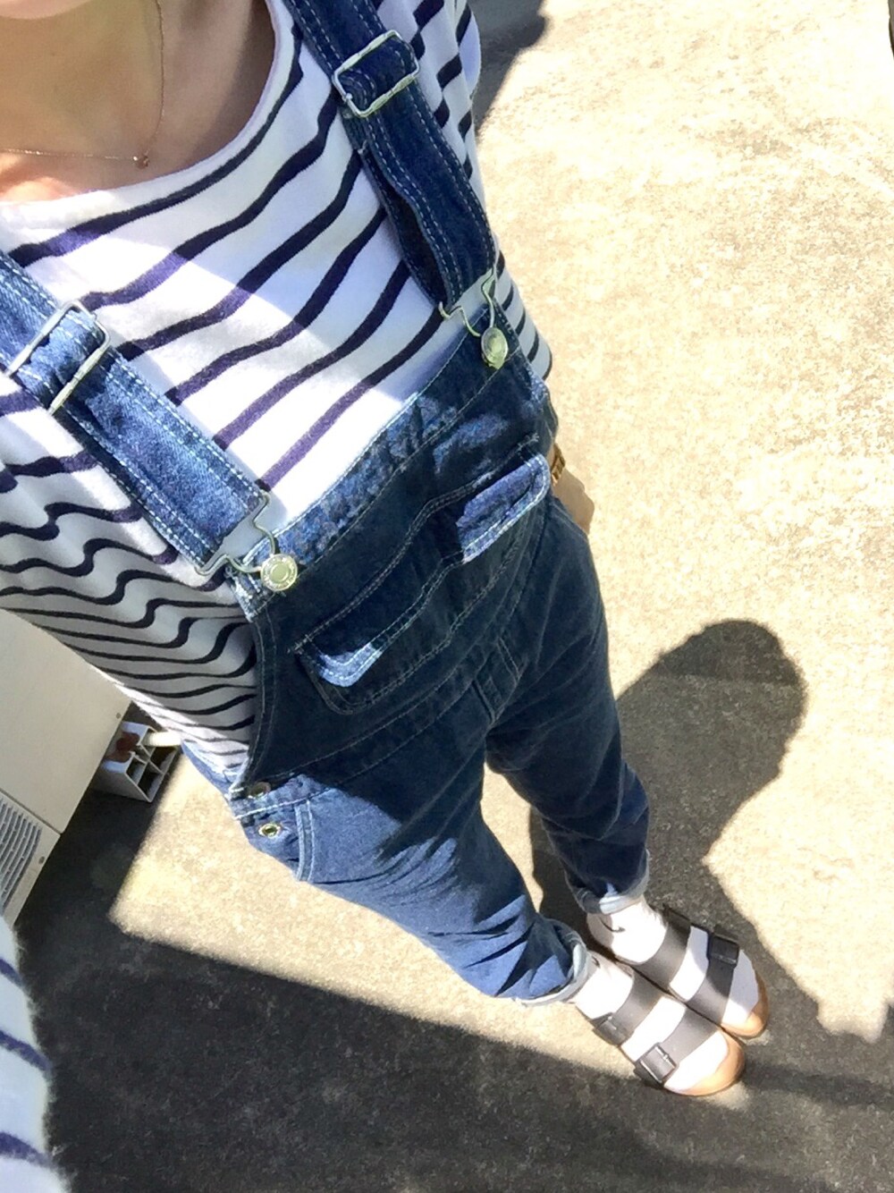 ブルー系のサロペット/オーバーオール、ホワイト系のTシャツ/カットソー、ブラック系のサンダルを着用したレディースの夏コーディネートの1枚目の写真