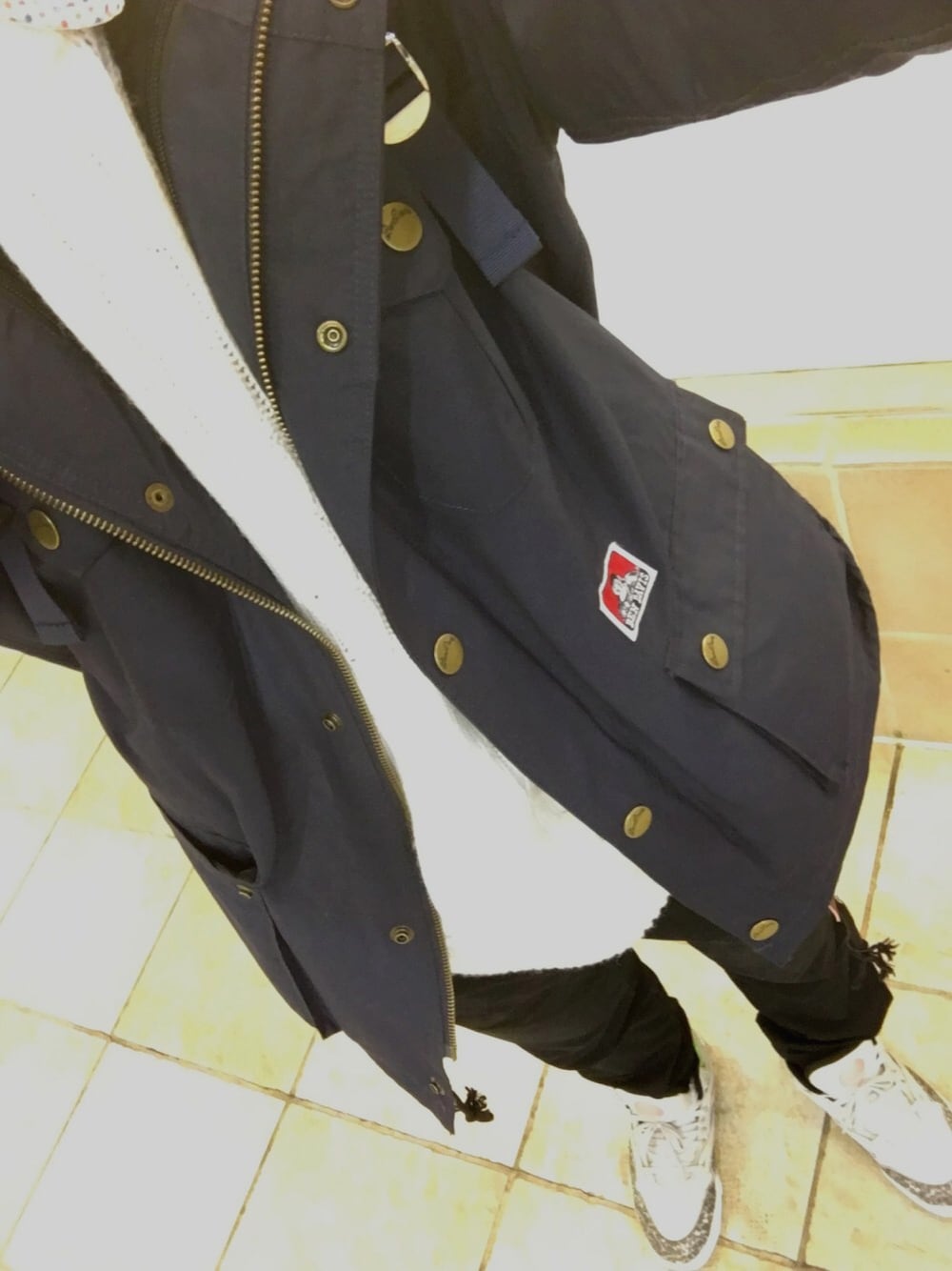 ブルー系のマウンテンパーカー、ホワイト系のニット/セーター、ブラック系のチノパンツを着用したメンズの冬コーディネートの1枚目の写真