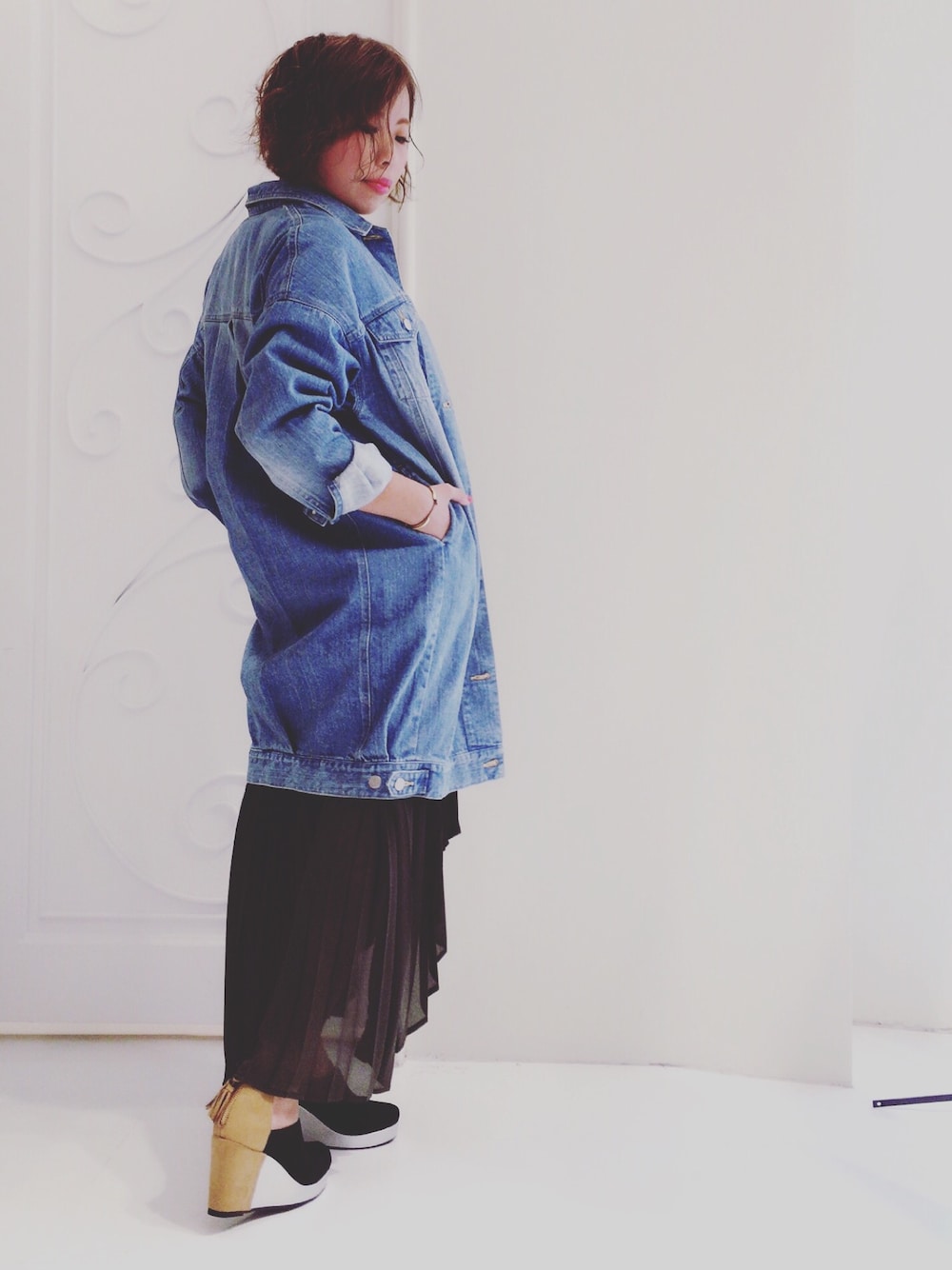 ブルー系のデニムジャケット、グリーン系のスカート、ブラック系のパンプスを着用したレディースの夏コーディネートの1枚目の写真