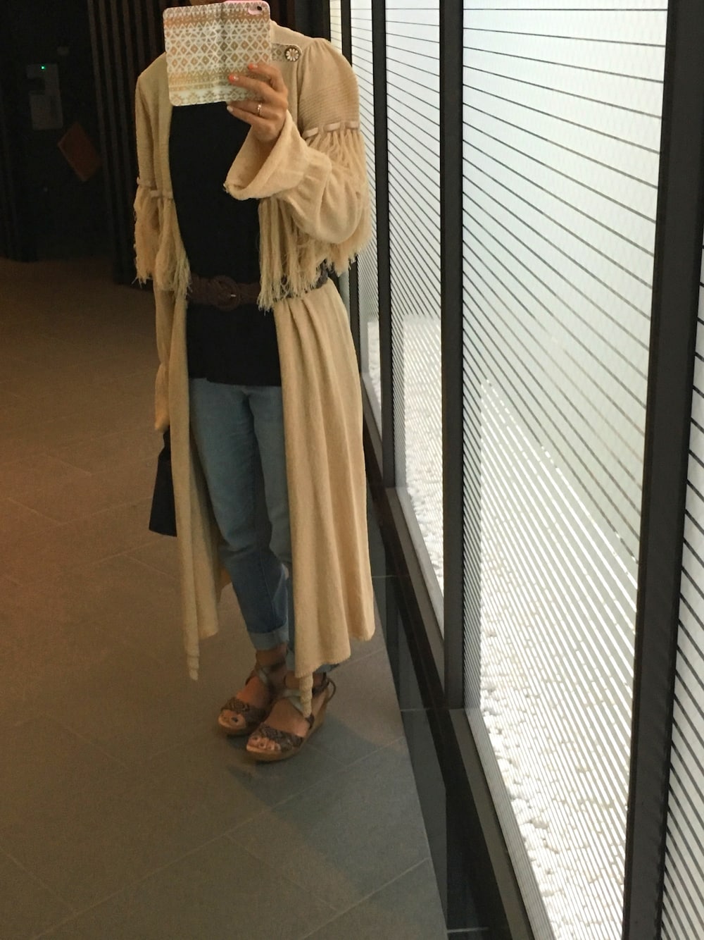 ベージュ系のカーディガン/ボレロ、ブラウン系のサンダル、ブラック系のTシャツ/カットソーを着用したレディースの春コーディネートの1枚目の写真