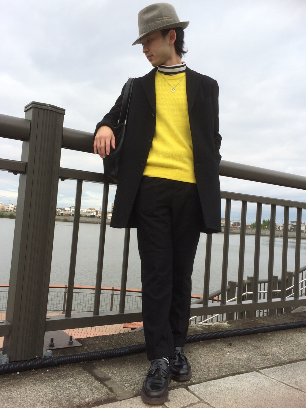 イエロー系のニット/セーター、ブラック系のトートバッグ、ブラック系のパンツを着用したメンズの秋コーディネートの1枚目の写真