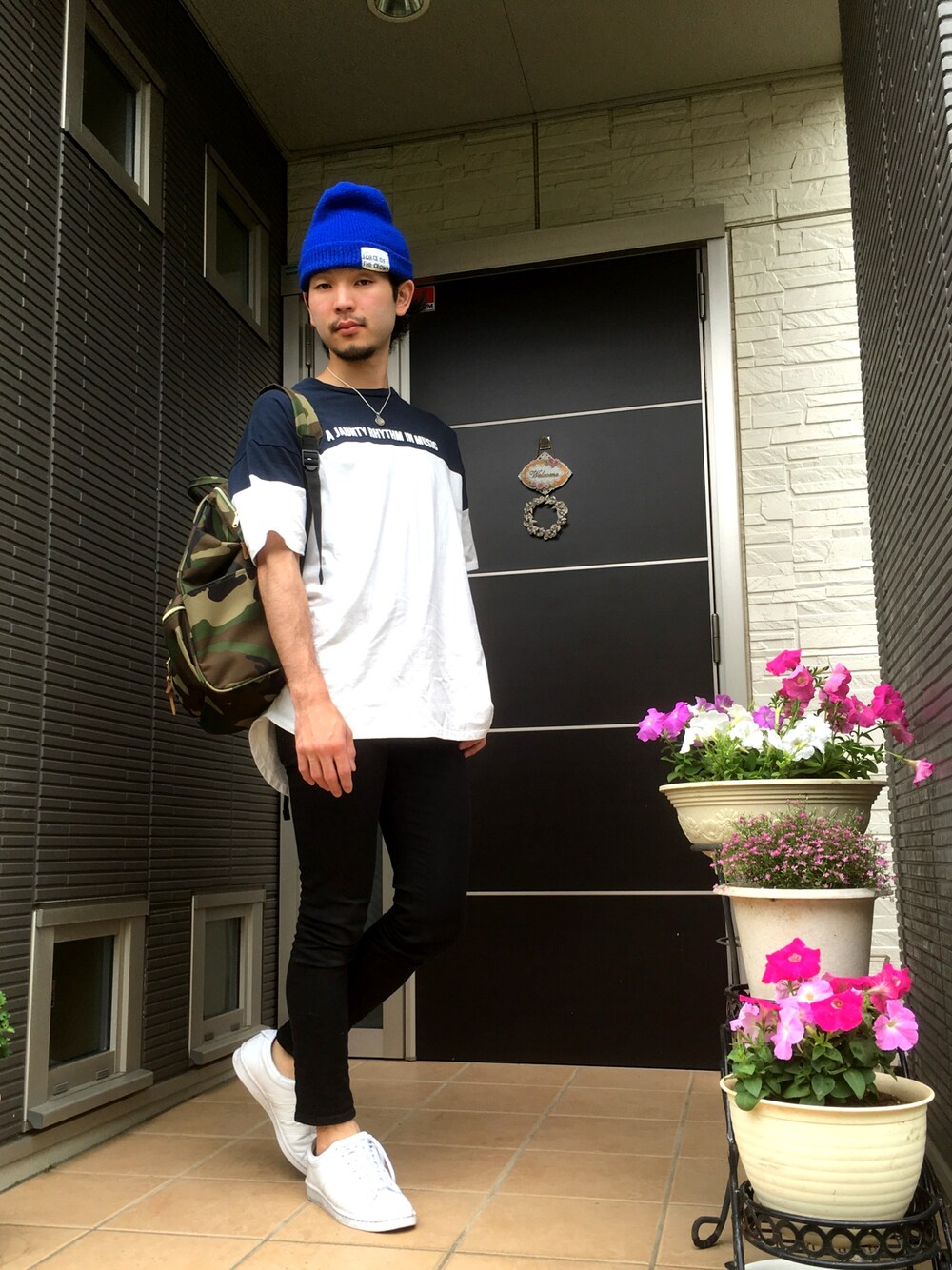 ブルー系のTシャツ/カットソー、ブラック系のパンツ、ホワイト系のスニーカーを着用したメンズの春コーディネートの1枚目の写真