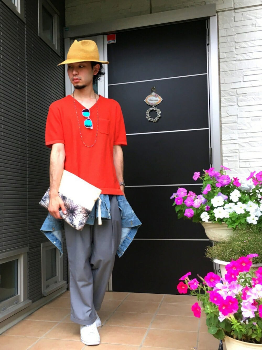 オレンジ系のニット/セーター、ブラック系のクラッチバッグ、グレー系のその他パンツを着用したメンズの夏コーディネートの1枚目の写真