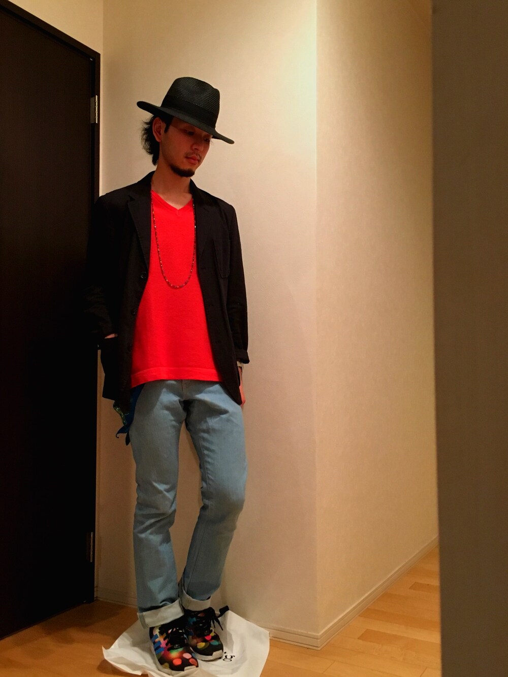 オレンジ系のニット/セーター、ブルー系のデニムパンツ、ブラック系のスニーカーを着用したメンズの夏コーディネートの1枚目の写真