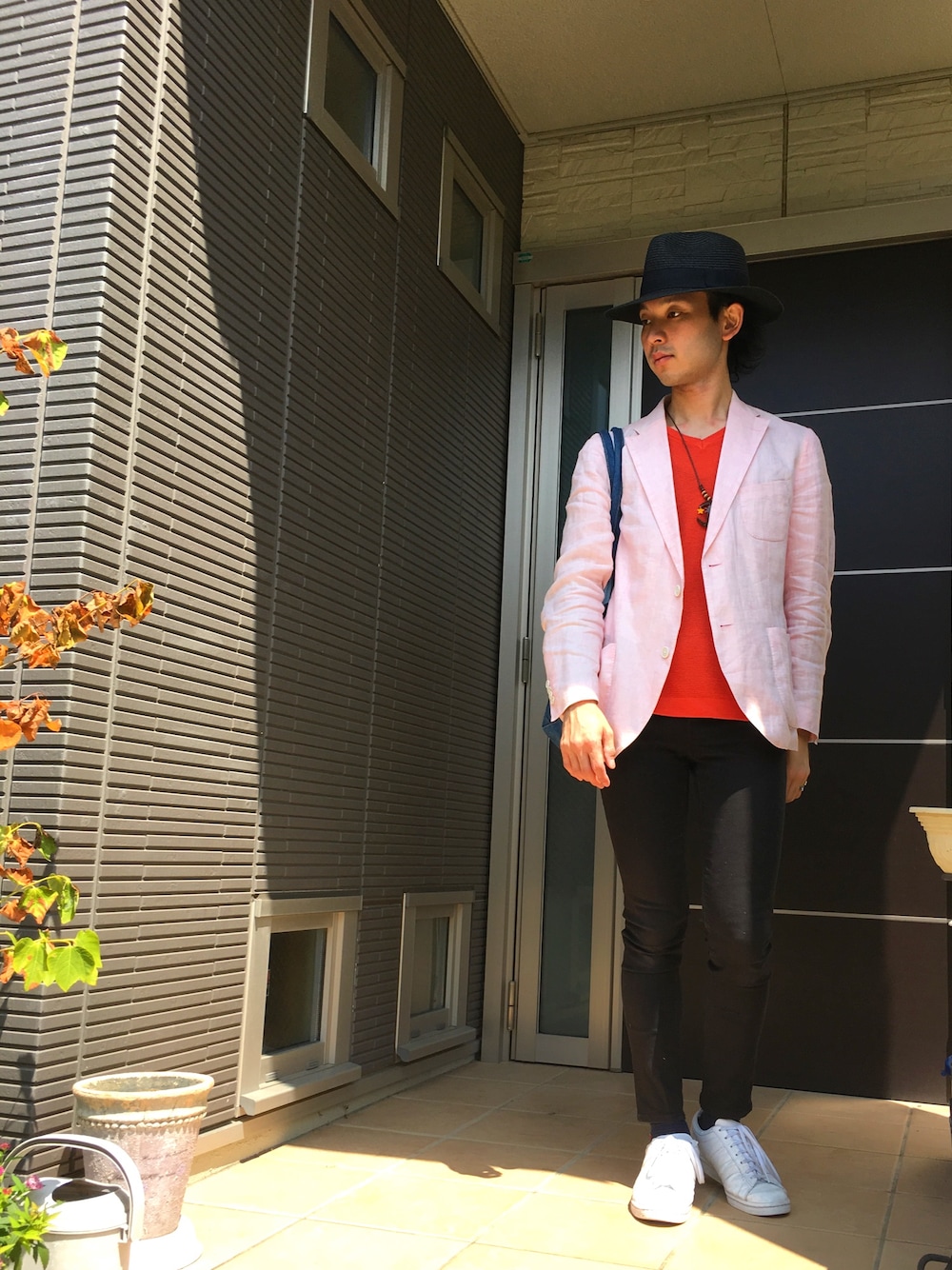 オレンジ系のニット/セーター、ピンク系のテーラードジャケット、ブラック系のパンツを着用したメンズの夏コーディネートの1枚目の写真