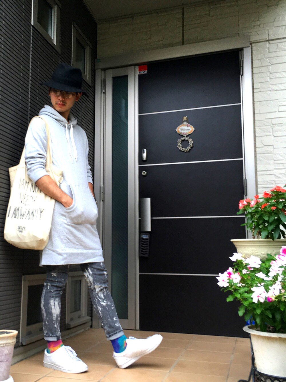 グレー系のワンピース、ブラック系のデニムパンツ、ホワイト系のスニーカーを着用したメンズの秋コーディネートの1枚目の写真