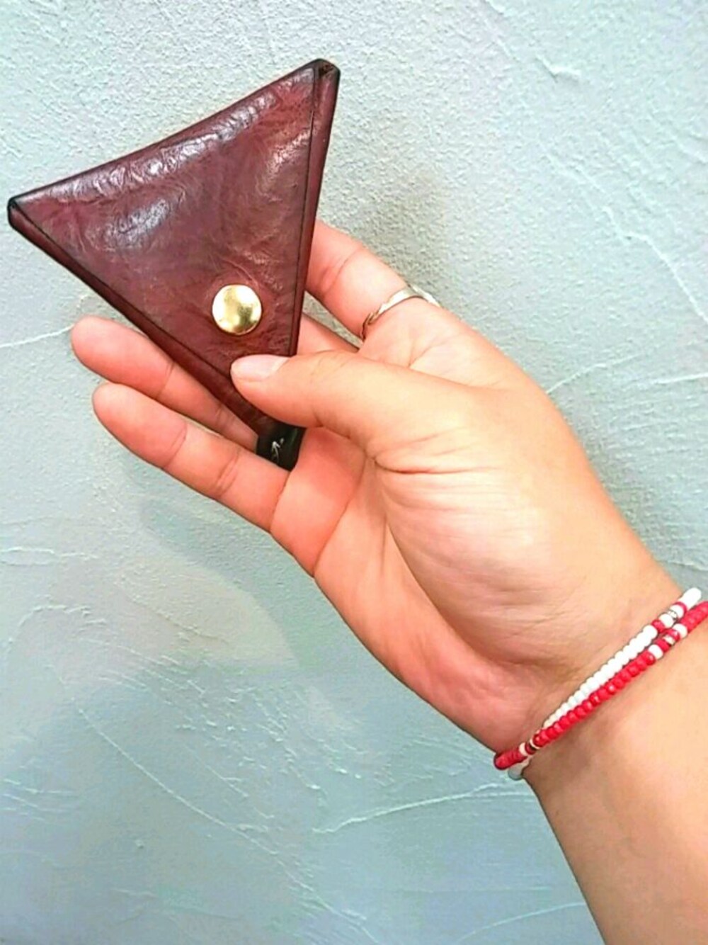 イエロー系のコインケース、ホワイト系のブレスレット、レッド系のブレスレットを着用したメンズの夏コーディネートの1枚目の写真