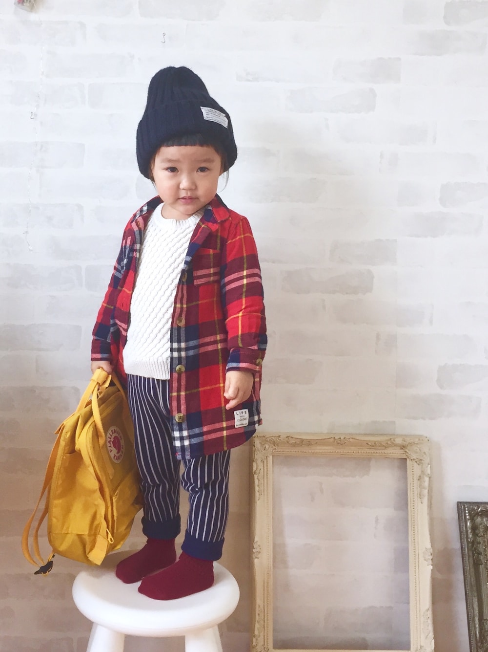 「2歳、女の子、キッズコーデ、キッズファッション、ストライプ、赤チェック、白ニット、ニット帽、カンケン」｜「GUのアイテム（ニットキャップ/ビーニー、ブラック系）」を使った、_nagi_さん（キッズ・90cm）の冬コーディネートの1枚目の写真
