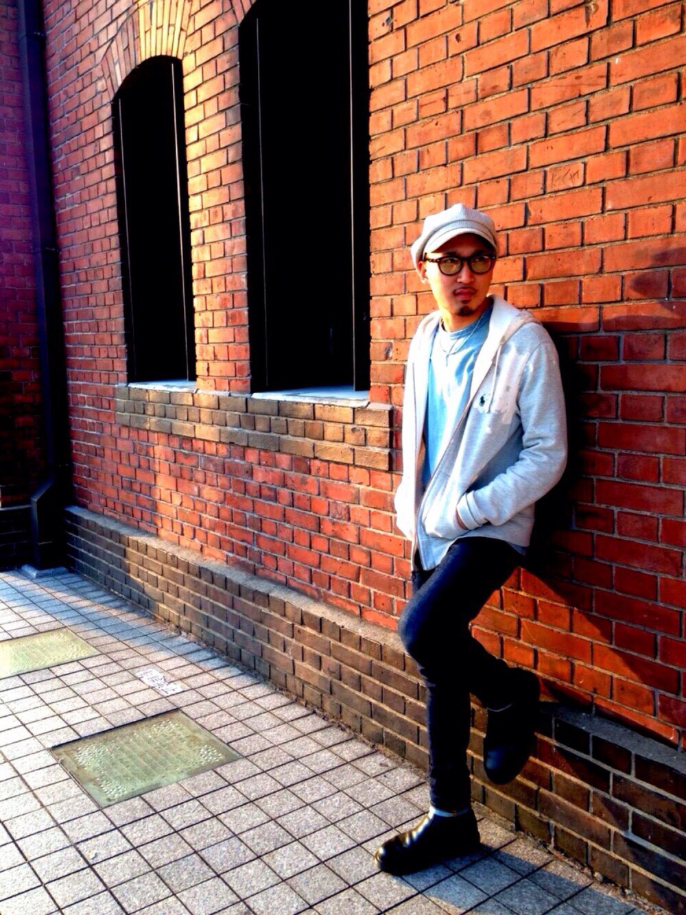 グレー系のパーカー、ブルー系のデニムパンツ、ベージュ系のキャスケットを着用したメンズの冬コーディネートの1枚目の写真