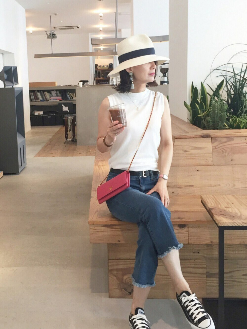 ブラック系のスニーカー、ブルー系のデニムパンツ、ホワイト系のニット/セーターを着用したレディースの夏コーディネートの1枚目の写真