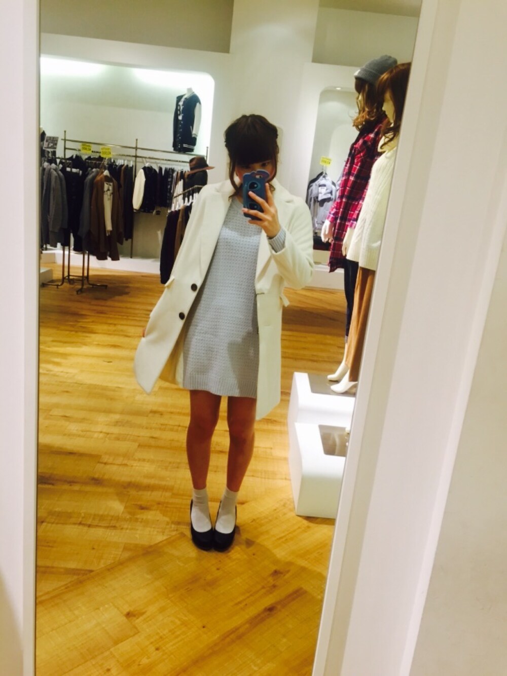 ブラック系のパンプス、ブルー系のチュニック、ホワイト系のチェスターコートを着用したレディースの秋コーディネートの1枚目の写真