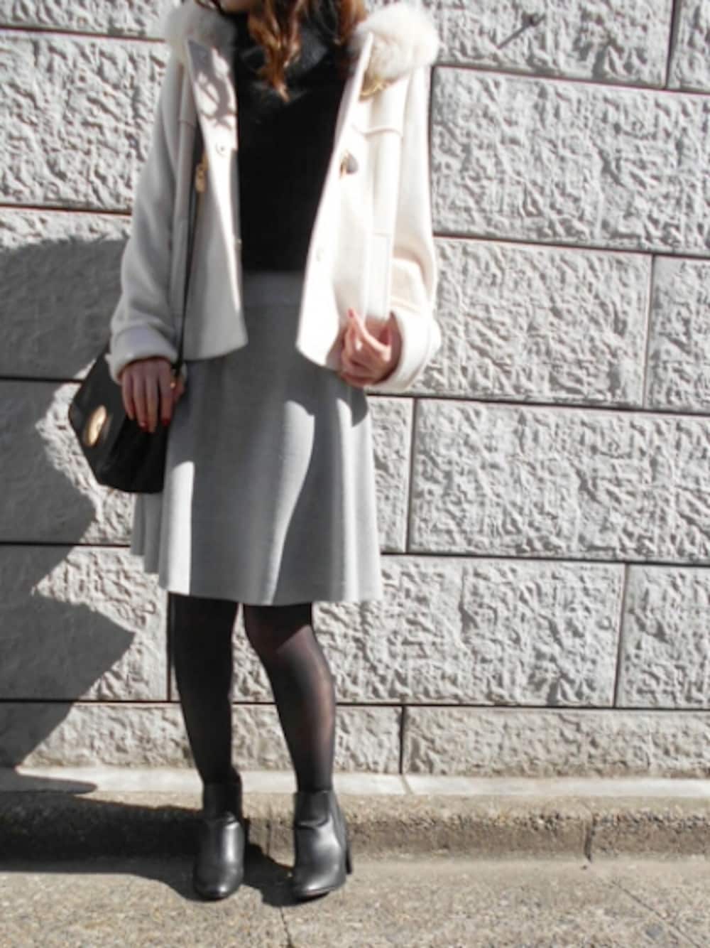 ホワイト系のダッフルコート、ブラック系のニット/セーター、グレー系のスカートを着用したレディースの秋コーディネートの1枚目の写真