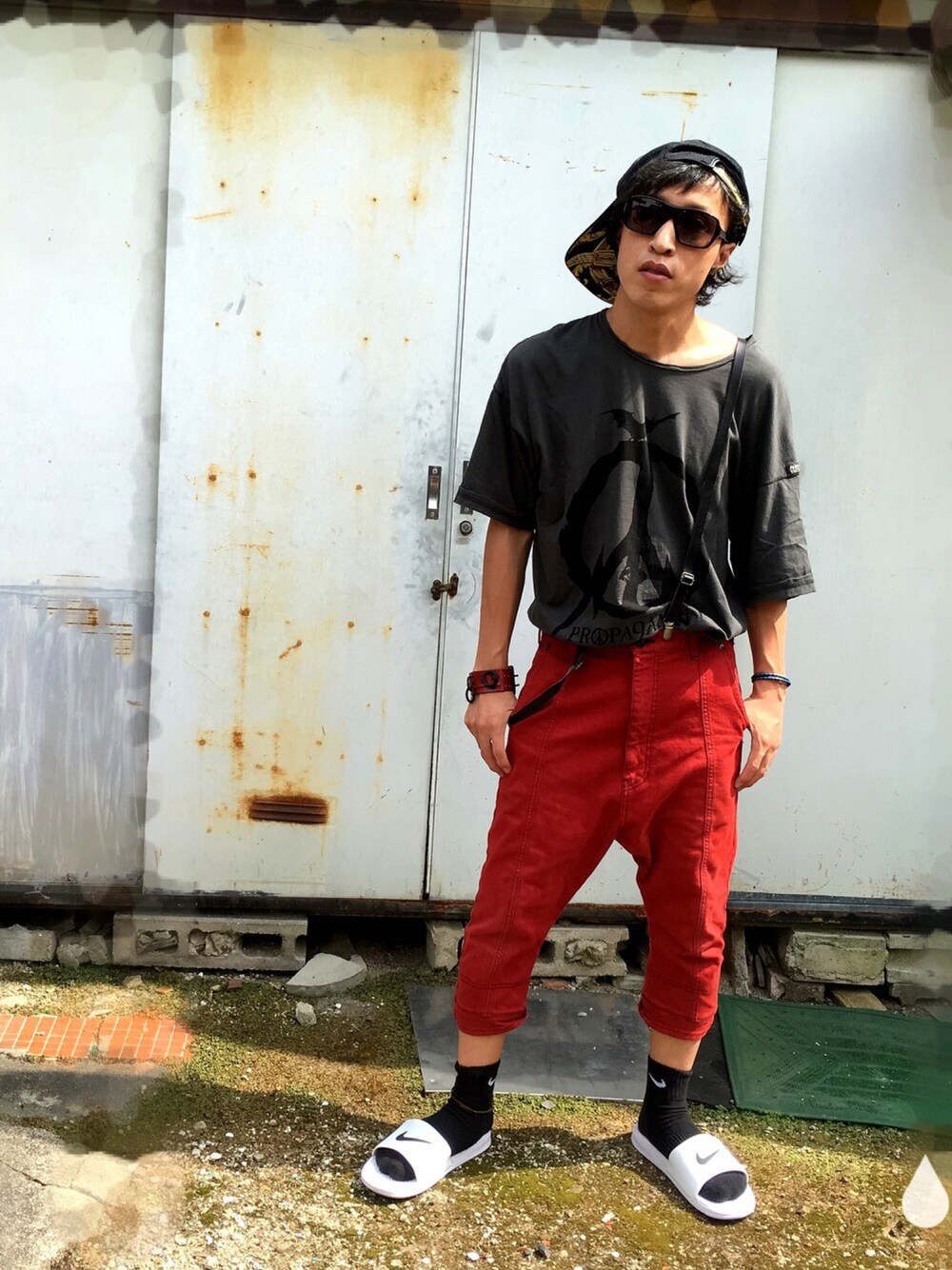 グレー系のTシャツ/カットソー、レッド系のデニムパンツ、ホワイト系のサンダルを着用したメンズの夏コーディネートの1枚目の写真