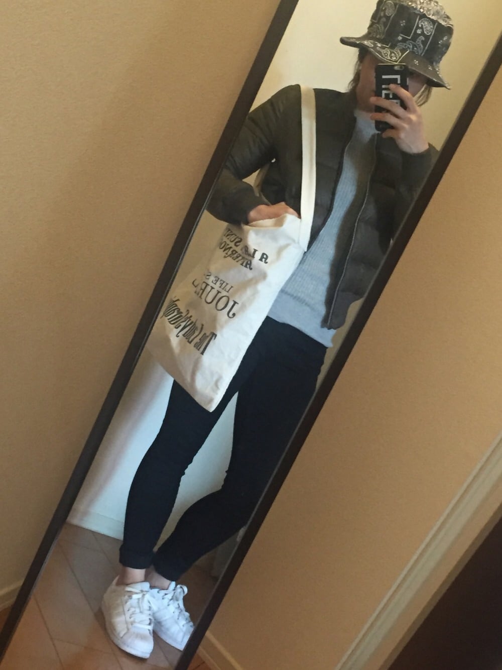 ホワイト系のトートバッグ、グリーン系のダウンジャケット/コートを着用したレディースの春コーディネートの1枚目の写真